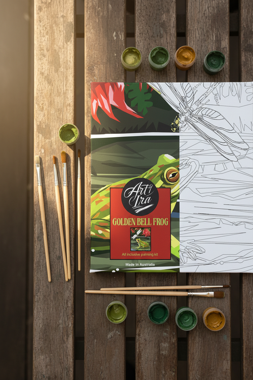 Art by Ira Golden Bell Frog painting kit flat lay with brushes and paint pots on wooden bench